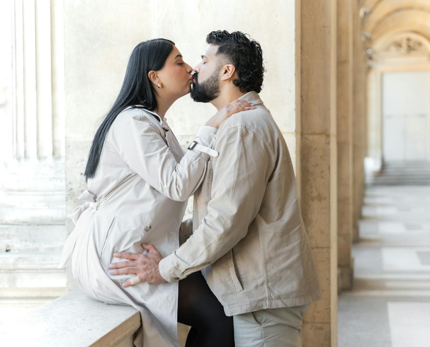 An elegant couple sharing a kiss in a European colonnade