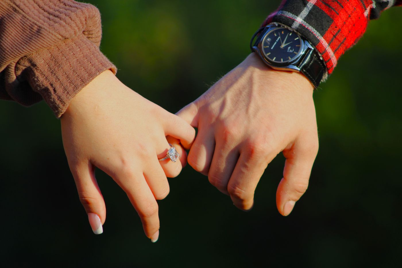 A diamond engagement ring on a couple's hands