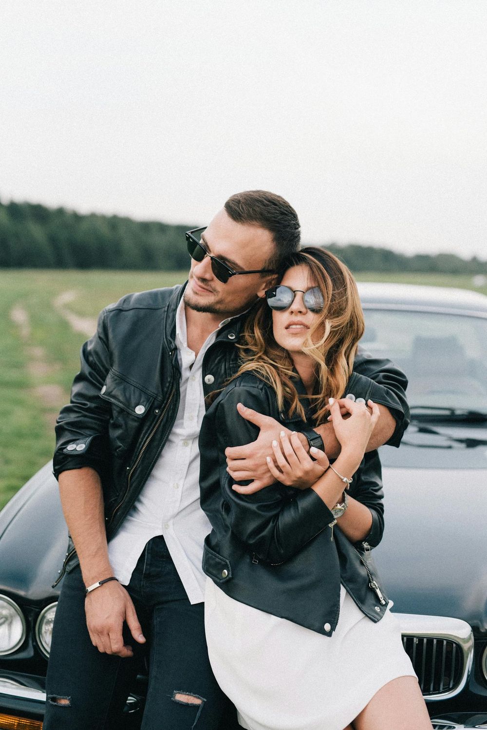A stylish couple beside a luxury car